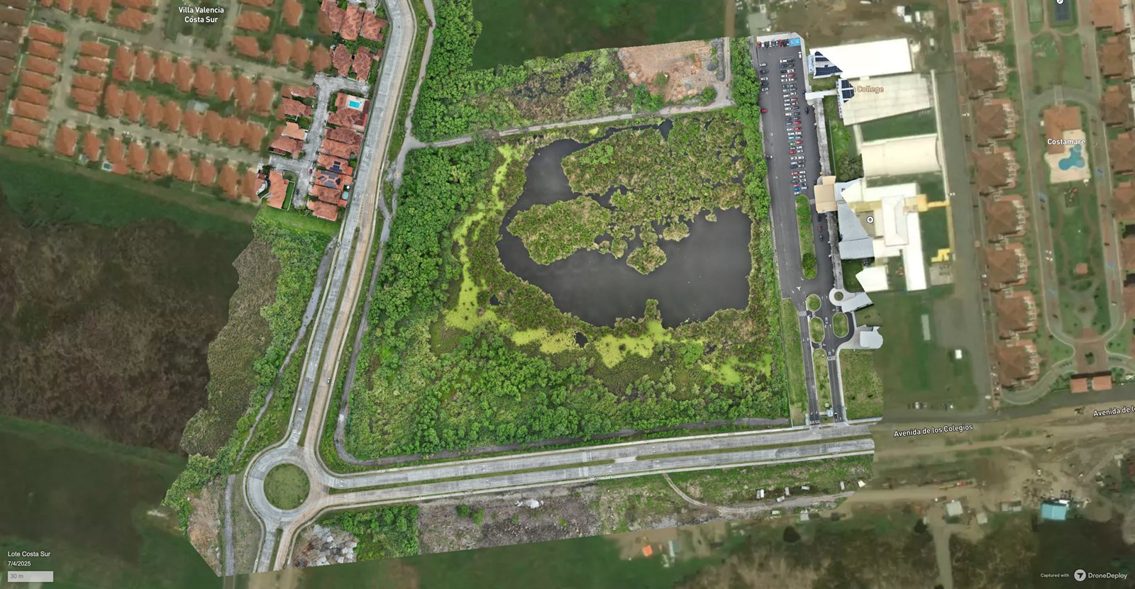 Vista aérea de un terreno con sus condiciones existentes, rotonda y laguna, antes del inicio de obra.